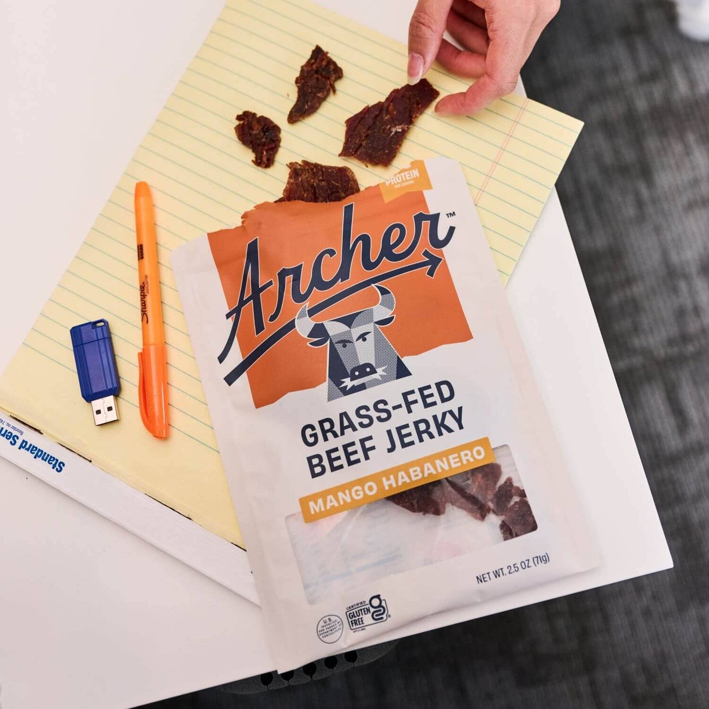 Archer Mango Habanero Beef Jerky open package on top of note pad on desk